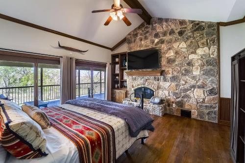 1 dormitorio con cama y pared de piedra en Tarcoola Riverfront Ranch, Billiards and Smart TVs en Bastrop