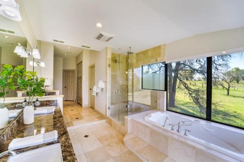 baño con bañera y ducha y ventana grande en Tarcoola Riverfront Ranch, Billiards and Smart TVs en Bastrop