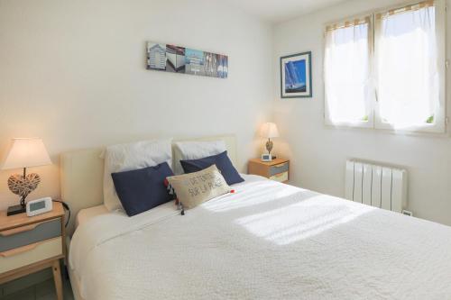 een slaapkamer met een groot wit bed met blauwe kussens bij ✦ Le Vol des Mouettes ✦ Port-Cogolin in Cogolin