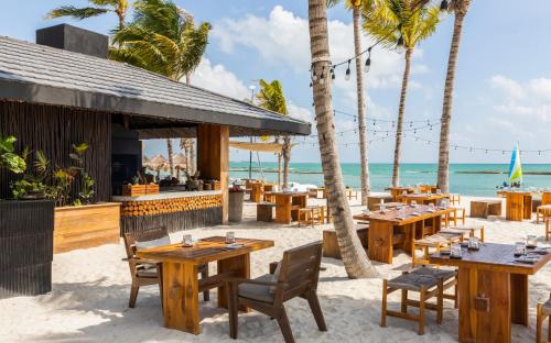 a restaurant on the beach with tables and chairs at Fairmont Mayakoba in Playa del Carmen
