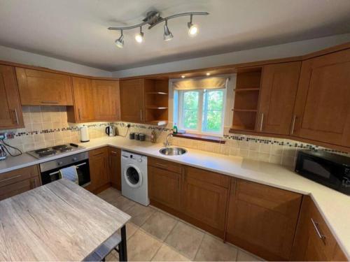 a kitchen with wooden cabinets and a sink and a dishwasher at Apartment with parking, close to the Raigmore hospital in Inverness