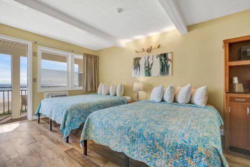 two beds in a room with a view of the ocean at Abellona Inn & Suites in Old Orchard Beach