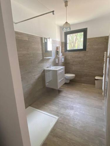 une salle de bain avec un lavabo et des toilettes et une fenêtre dans l'établissement U Primu Appartement spacieux au calme Aléria, à Aléria