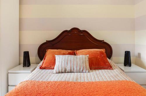 a bed with an orange comforter and two pillows at Cantinho da Lena in Sacavém