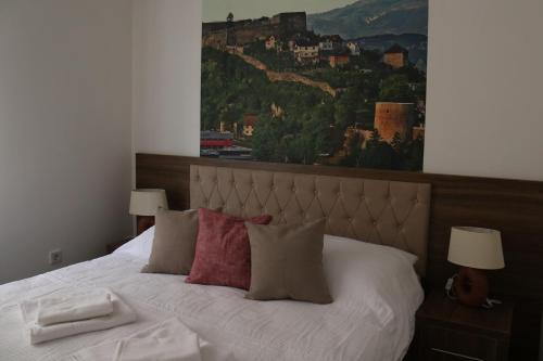 a bedroom with a bed with white sheets and red pillows at Royal City Apartments in Jajce