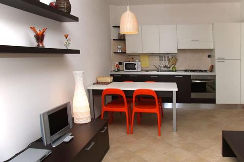 eine Küche mit zwei orangenen Stühlen und einem Tisch mit einem TV in der Unterkunft Sass Negher in Valmadrera