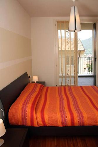 ein Schlafzimmer mit einem Bett mit einer orangefarbenen gestreiften Decke in der Unterkunft Sass Negher in Valmadrera