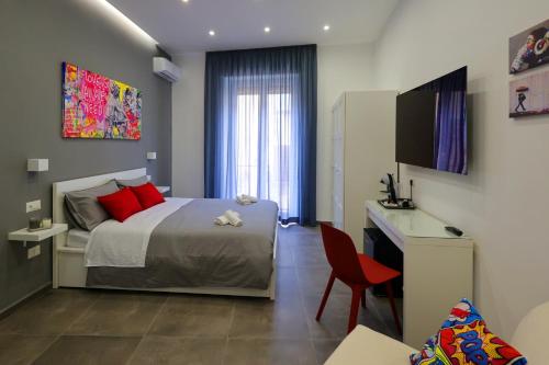 - une chambre avec un lit, un bureau et une télévision dans l'établissement Napolitan Pop House, à Naples