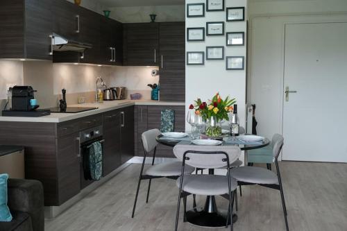 une cuisine et une salle à manger avec une table et des chaises dans l'établissement Le Saint Val 004, Appart. neuf, jardin, parking, à Saint-Valery-sur-Somme