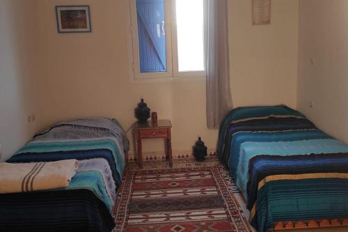 twee bedden in een kamer met een raam bij Riyad Azul entre nature et océan in Sidi Kaouki