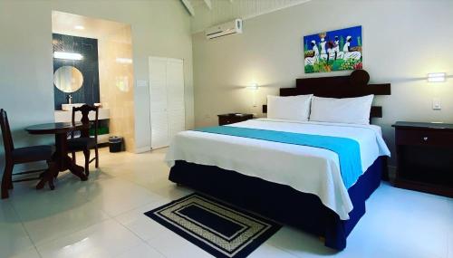 a bedroom with a large bed and a table and chair at THE BOARDWALK VILLAGE in Negril