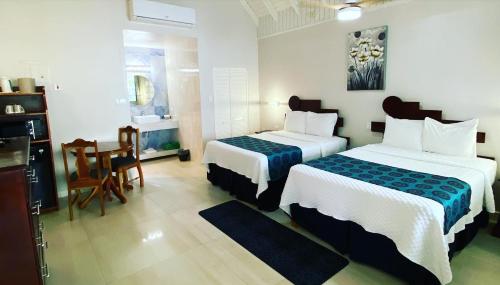 Habitación de hotel con 2 camas, mesa y sillas en THE BOARDWALK VILLAGE en Negril