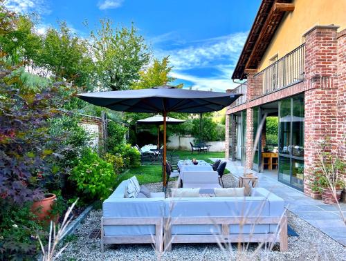 a patio with white couches and an umbrella at MiaClara Relais in Alba