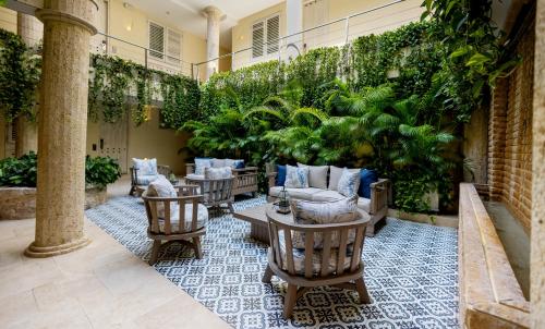 eine Terrasse mit Stühlen, Tischen und Pflanzen in der Unterkunft Hotel Casa Canabal by Faranda Boutique in Cartagena de Indias