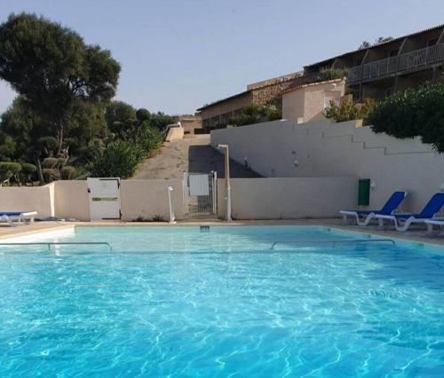 une grande piscine avec des chaises bleues et un mur dans l'établissement mini villa 72, résidence avec piscine., à Serra-di-Ferro
