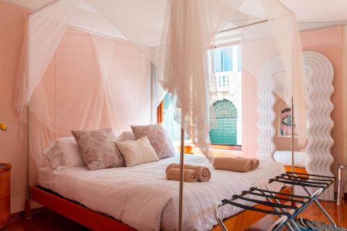 a bedroom with a white canopy bed with a window at Casa Flavia ai Morosini - Luxury apartment with Canal View in Venice