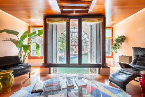 a living room with a glass table and a large window at Casa Flavia ai Morosini - Luxury apartment with Canal View in Venice