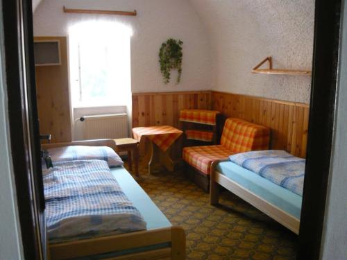 Cette chambre dispose de deux lits, d'une chaise et d'une fenêtre. dans l'établissement Penzion Ski, à Karlova Studánka