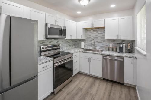 a kitchen with white cabinets and stainless steel appliances at Four Bedroom Home Near Hartsfield Jackson Airport in Riverdale