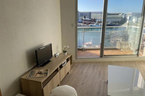 ein Wohnzimmer mit einem TV und einem großen Fenster in der Unterkunft Pretty and bright studio with view on the harbor in Les Sables-dʼOlonne