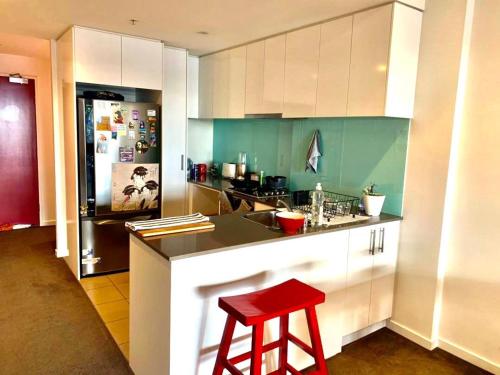 a kitchen with a red stool and a refrigerator at Shared Homestay Tranquil Art Deco Private Room with Private Bathroom In Brunswick in Melbourne