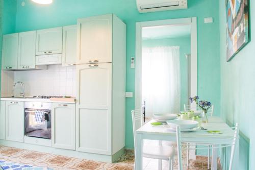 a kitchen with blue walls and a table and a table and chairs at Appartamenti Celestina Portoferraio in Portoferraio