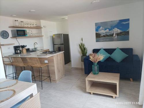 a living room with a blue couch and a kitchen at Apto Nuevo, Tranquilo, Bonito, 5 min Plaza Principal in Guatapé