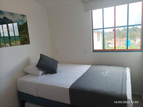 a bed sitting in a room with a window at Apto Nuevo, Tranquilo, Bonito, 5 min Plaza Principal in Guatapé