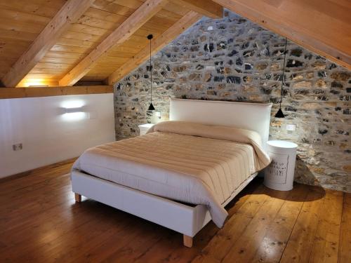 1 dormitorio con cama y pared de piedra en Casolare Cento Ulivi Luxury & Charme, en Ascea