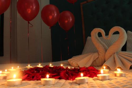 a group of candles and red roses on a bed with swans at hotel marsella in Sonsonate