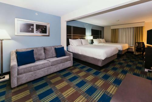 La Quinta Inn & Suites by Wyndham Ankeny IA - Des Moines IA في انكيني: غرفه فندقيه بسرير واريكه