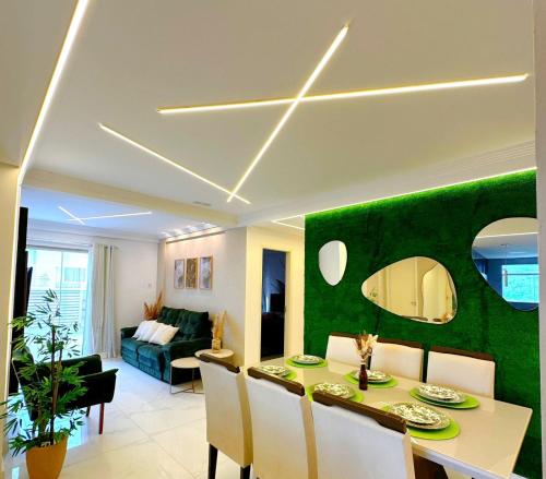 sala de estar con mesa y pared verde en Coberturas ou apartamentos 1min da praia do recreio com Vista Mar, en Río de Janeiro