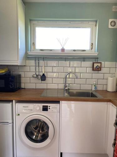 a kitchen with a washing machine and a sink at Gorton House and Cottages in Lasswade