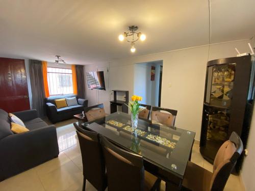 a dining room and living room with a table and chairs at Apart La Posada in Tacna