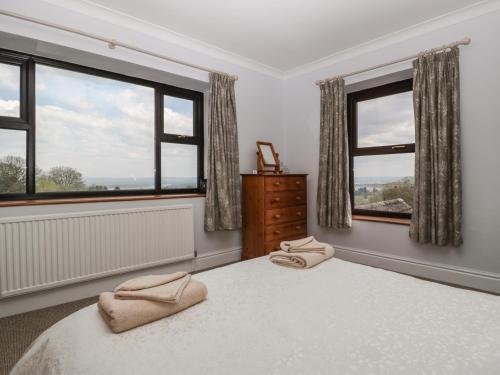 a bedroom with windows and a bed with two towels on it at Moors Farm in Cinderford