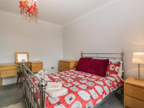 a bedroom with a bed with a red and white quilt at Moors Farm in Cinderford