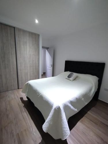 a bedroom with a white bed with a black headboard at Departamento Tandil in Tandil