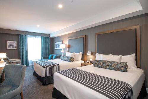 a hotel room with two beds and a chair at Sandman Signature Ottawa Airport Hotel in Ottawa