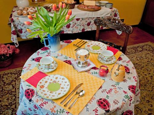 - une table avec des assiettes et des ustensiles dans l'établissement Le Coccinelle B&B, à Grignasco