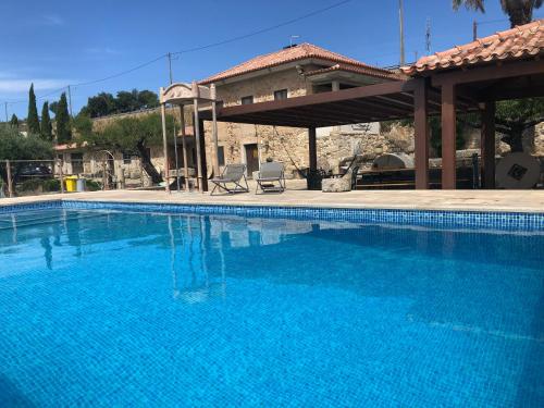 uma grande piscina azul em frente a uma casa em Quinta das Pias - Holiday Farm em Pinhel