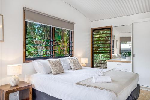 sypialnia z dużym białym łóżkiem i oknem w obiekcie Fuller Holidays - Belongil Beachfront Pavilion, 18 Childe St w mieście Byron Bay