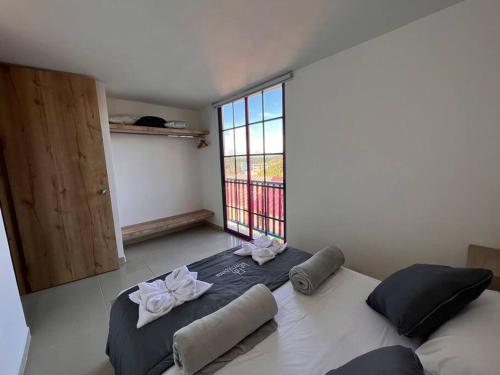 a bedroom with a large bed with a large window at Apto Nuevo, Tranquilo a 5 min Plaza Principal in Guatapé
