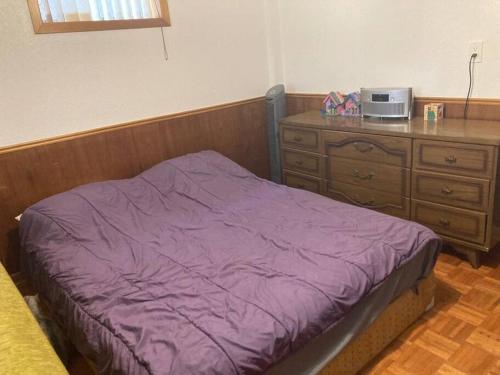 - une chambre avec un lit violet et une commode dans l'établissement Walkout Apartment with a spacious backyard in the Ravine, à Toronto