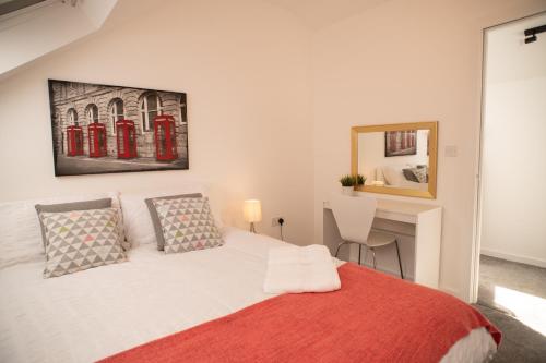 基德靈頓的住宿－Walnut Flats-F3, 1-Bedroom with Stunning Garden View, AC, Parking, Netflix, WIFI - Close to Oxford, Bicester & Blenheim Palace，一间卧室配有一张带红色毯子的床和一张书桌