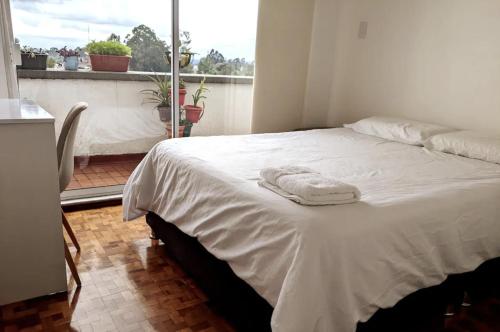 a white bed in a room with a window at Habitación en COLIVING penthouse centro histórico in Popayan