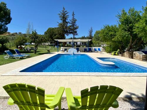uma piscina com duas cadeiras verdes ao lado de uma casa em Quinta Alfaval em Redondo