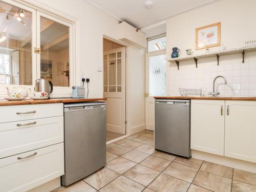 a kitchen with white cabinets and stainless steel appliances at Banneth in Mawgan in Meneage