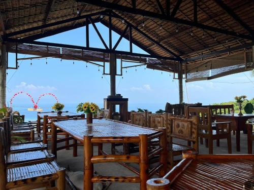 a restaurant with tables and chairs with a view of the ocean at Thornton's Sea View Cafe & Guesthouse in Siquijor
