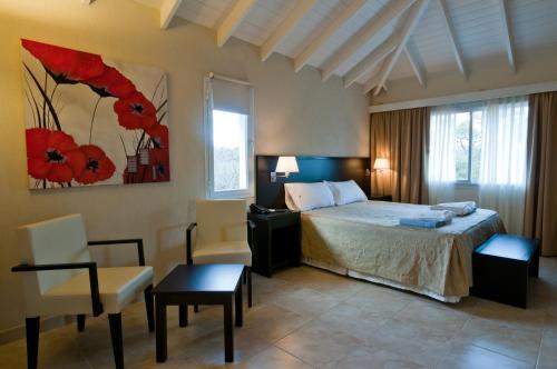 um quarto com uma cama, uma secretária e cadeiras em Álamos del Mar Apart Hotel & Spa em Valeria del Mar
