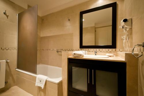 uma casa de banho com um lavatório, um chuveiro e um espelho. em Álamos del Mar Apart Hotel & Spa em Valeria del Mar